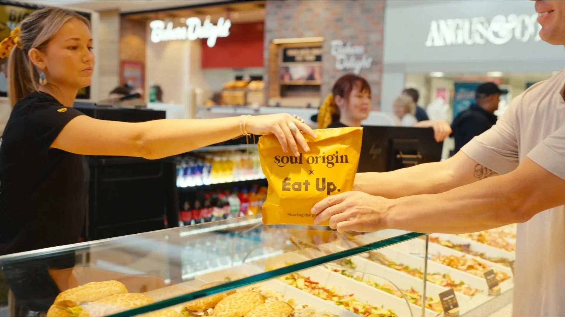 A Soul Origin employee hands a bag to a customer.