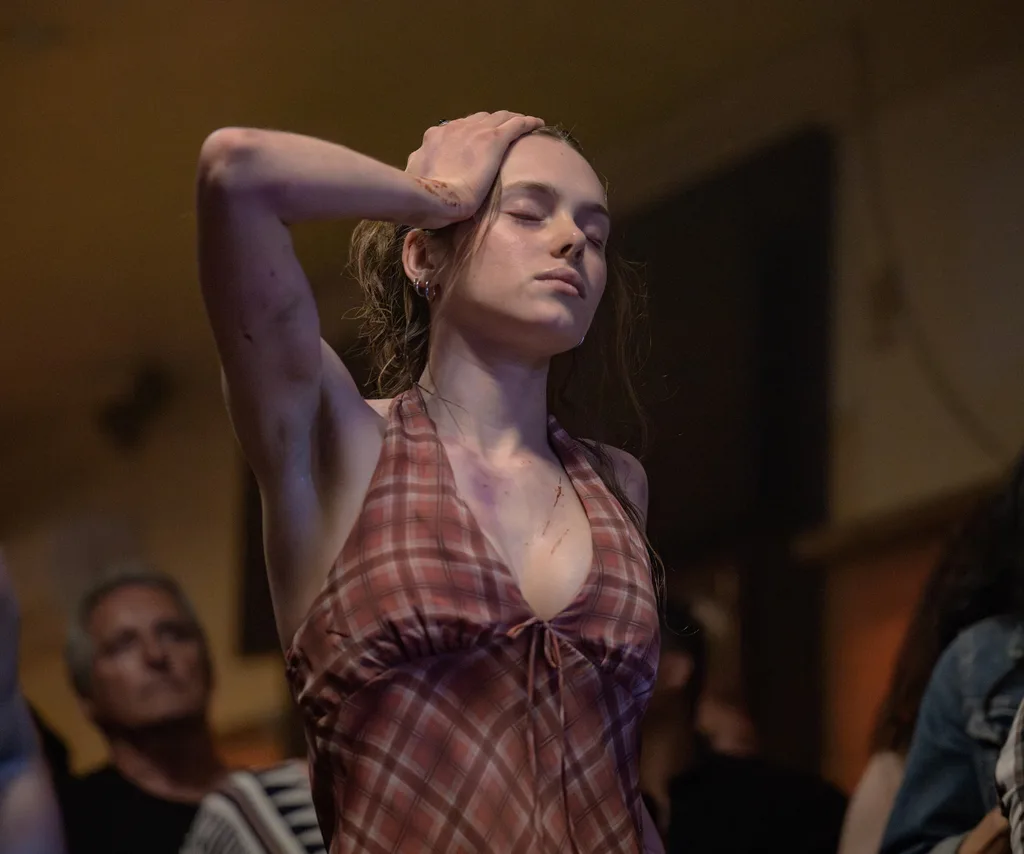 Zoe Phillips, as Edie, with visible injuries, dances with her eyes closed.