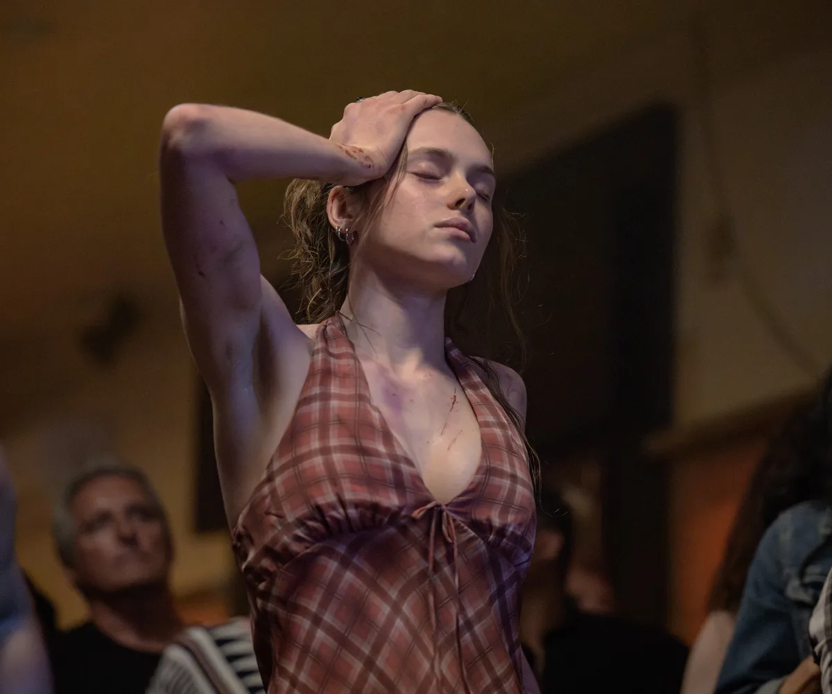 Zoe Phillips, as Edie, with visible injuries, dances with her eyes closed.