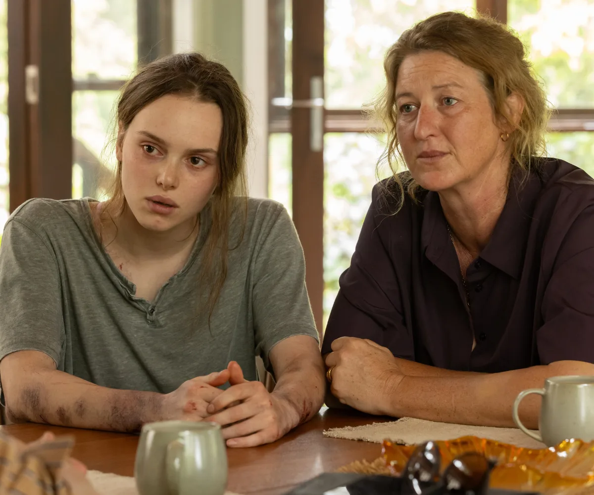 Zoe, in character as Edie, sits next to Kate Box at a table on the set of Dustfall