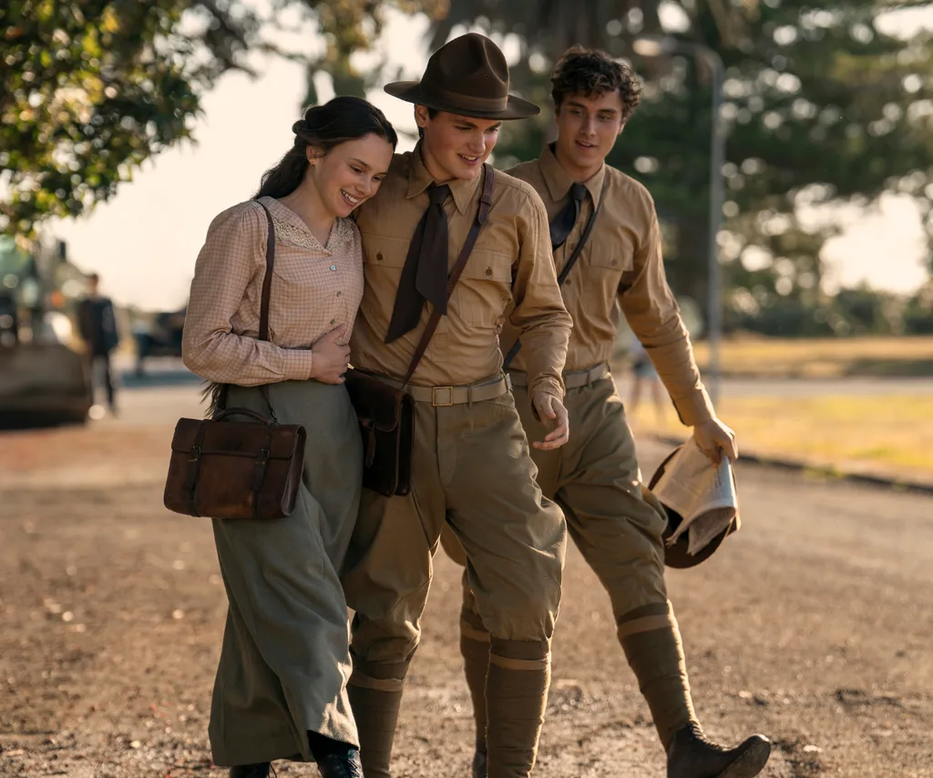 Edie, as Abra in East Of Eden, walks down a dusty road with two young men in uniform.