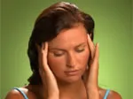 Woman with a headache holding her temples, eyes closed, set against a green background.
