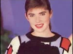 Young woman smiling, wearing a colorful knit sweater, against a purple background.