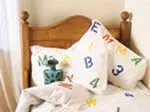 Wooden bed with stenciled letter-patterned pillows and bedding.