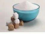 Bowl of white sugar with brown and white sugar cubes beside it on a light background.