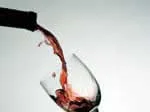 Wine being poured into a glass from a bottle against a light background.