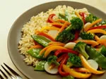 A plate of mixed vegetables with broccoli, bell peppers, and rice, arranged on a white table.