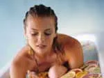 A woman with braided hair relaxes, surrounded by sliced citrus fruits on a smooth surface.