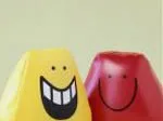 Two stress balls with smiling faces, one yellow and one red, against a pale background.