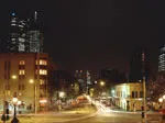 City street at night with blurred car lights and tall buildings in the background.