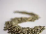 Dried pumpkin seeds scattered on a smooth, light surface in an abstract pattern.