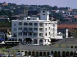 Colonial-style building near a waterfront with cityscape in the background.
