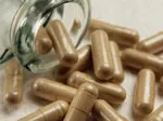 Brown capsules spilling from a glass jar onto a surface.