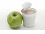Green apple beside an open yogurt cup on a white background.