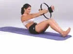 Woman performing Pilates exercise on mat with a resistance ring, sitting with legs bent.