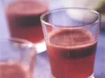 Glasses filled with a thick, red smoothie, sitting on a table.