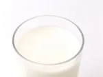 A glass of milk filled to the brim, captured against a white background.