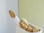 Basket of freshly baked baguettes against a two-tone wall backdrop.