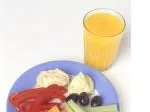 Plate with sliced peppers, hummus, celery, olives, and a glass of orange juice on the side.