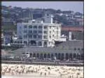 Bondi Beach with a bustling crowd in front of the iconic Bondi Pavilion on a sunny day.