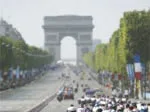 Cyclists racing in front of the Arc de Triomphe in Paris, with a crowd gathered along the Champs-Élysées.