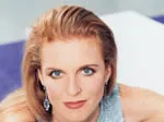Female with long hair, wearing a blue top, looking at the camera.