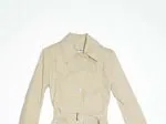 Beige trench coat on white background, iconic classic fashion staple, buttoned front with belt.