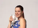 Woman in a floral dress smiling and holding a glass of milk.