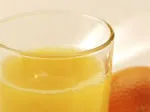 Glass of orange juice beside an orange, used as a remedy in treating hangovers.