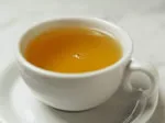 A steaming cup of tea on a saucer placed on a white surface.