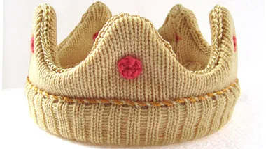 A knitted crown with red dots, suitable for dressing up young children in a royal theme.