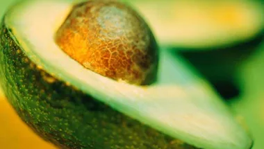 Close-up of a halved avocado with a visible pit, showcasing its textured skin and creamy interior.
