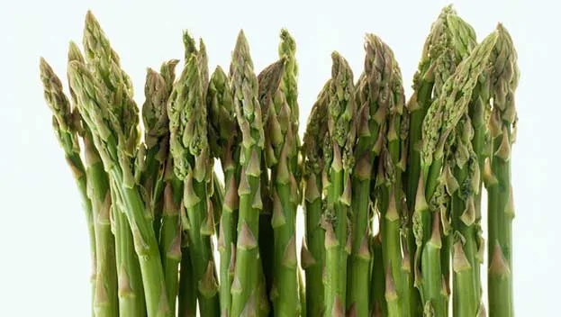 Fresh green asparagus spears standing upright against a light background.