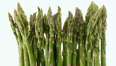 Fresh green asparagus spears standing upright against a light background.