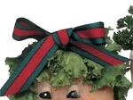 Vegetable sculpture with a leafy head, large striped bow, and expressive eyes, partially visible.