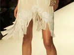 Cream dress with lace and fringe detailing at the hem, worn by a model on the runway.