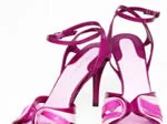 Purple high-heeled sandals with ankle straps and decorative bow accents on a white background.