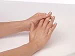 Hands with natural nails resting on a white surface.