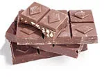 Stack of milk chocolate squares with a few pieces containing nuts.