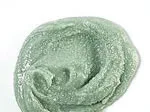 Green exfoliant scrub with a creamy texture on a white background.