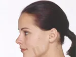 A woman with brown hair in a ponytail displays different foundation shades on her cheek to match skin tone.