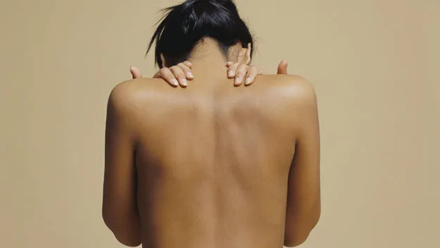 "Person holding their upper back, illustrating back pain relief techniques."