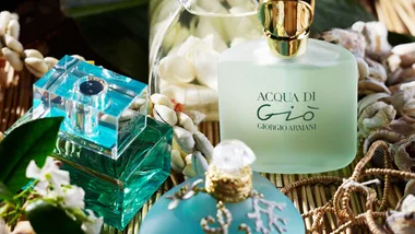 Bottles of Acqua di Giò by Giorgio Armani with seashells and tropical decorations.