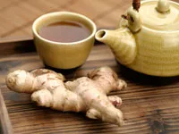 Tea set with cup and teapot, ginger root on a wooden tray.