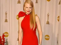Nicole Kidman in a red dress poses at an event with ABC logos in the background.