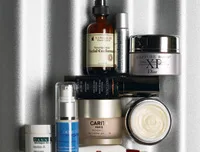 A collection of various skincare products, including serums, creams, and lotions, arranged on a textured surface.