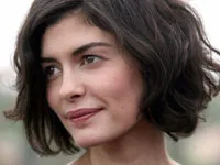 Audrey Tautou with short wavy hair, looking to the side with a slight smile.