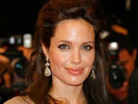 Celebrity with long hair and earrings at a public event, smiling towards the camera.