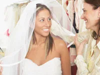 Bride trying on wedding dress with a friend in a bridal shop, surrounded by gowns.