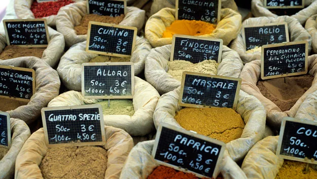 A variety of spices in bags with labels and prices at a market.